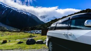 Compacte camper op de voorgrond met achteraan een rij motorhomes. Locatie: kampeerterrein bij Mt Cook