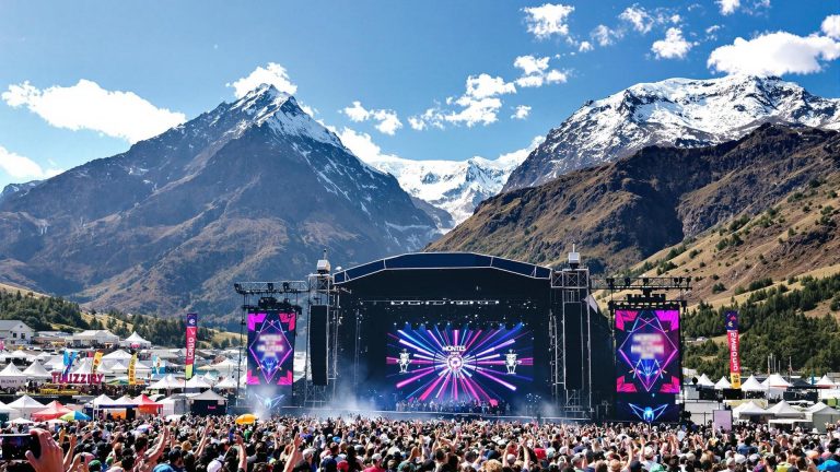 Festival tussen de bergen: podium en dansende mensen ervoor met bergen in de achtergrond
