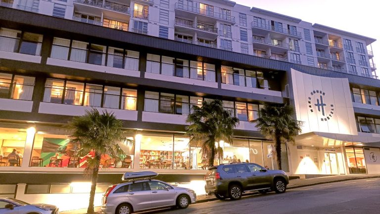 Haka House Auckland City in de avond, lichten aan en mensen in de gemeenschappelijke ruimtes